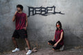 Two people in matching outfits against a wall with 'REBEL' graffiti.